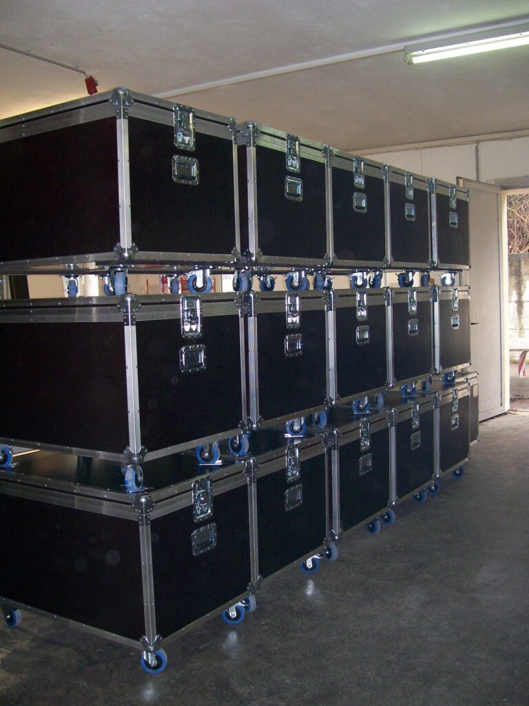 Gestapelte Flightcases mit blauen Lenkrollen – neun kleine und drei große Transportkoffer, gefertigt von LIHA, Steyregg